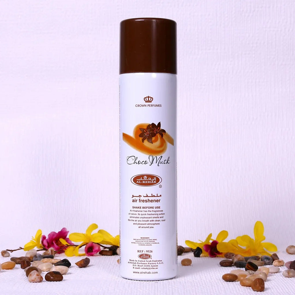 Choco Musk Air Freshener by Al Rehab – 300ml can surrounded by decorative flowers and stones, perfect for creating a warm and inviting atmosphere.